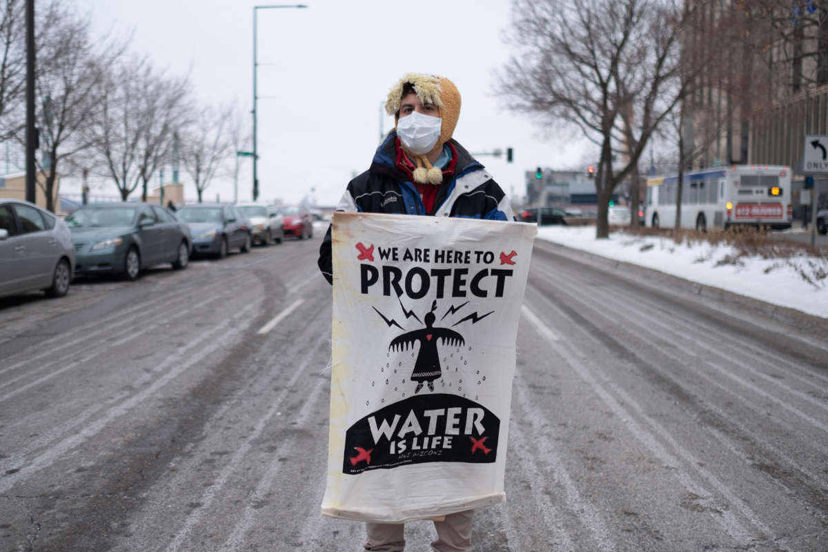 A person displays a sign reading "WE ARE HERE TO PROTECT; WATER IS LIFE"