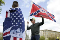 Keith Weber of Centralia, Washington, holds a flag that combines a Gadsden flag from the American Revolution with a Confederate flag from the U.S. Civil War as he talks to protesters holding flags with then-President Donald Trump on them as people demonstrate against Washington State's stay-home order at the state capitol in Olympia, Washington, on April 19, 2020.