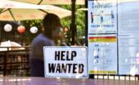 A "Help Wanted" sign is posted beside Coronavirus safety guidelines in front of a restaurant in Los Angeles, California, on May 28, 2021.