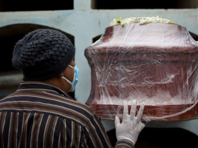 A man touches the coffin of his relative who died of COVID-19 on June 1, 2021, in Lima, Peru.
