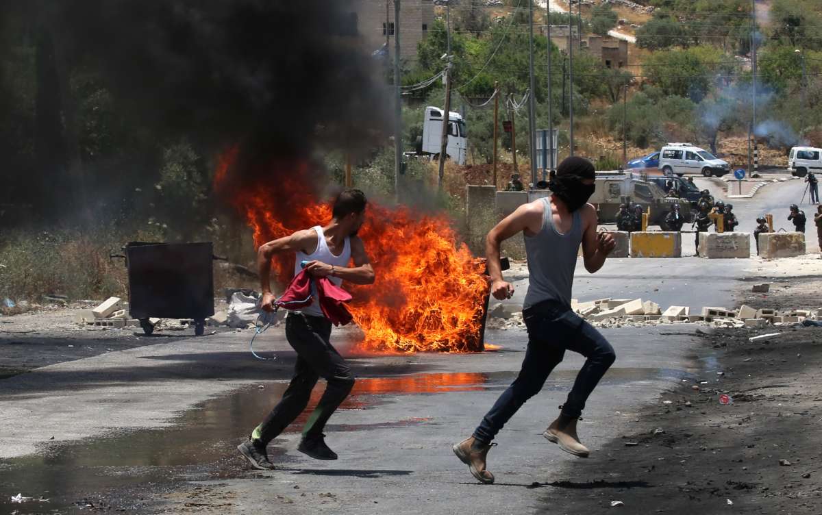 Palestinian protesters run to take cover during a protest against the expanding of Jewish settlements and the Israeli annexation plan in the village of Beita, south of the West Bank city of Nablus, on June 8, 2021.