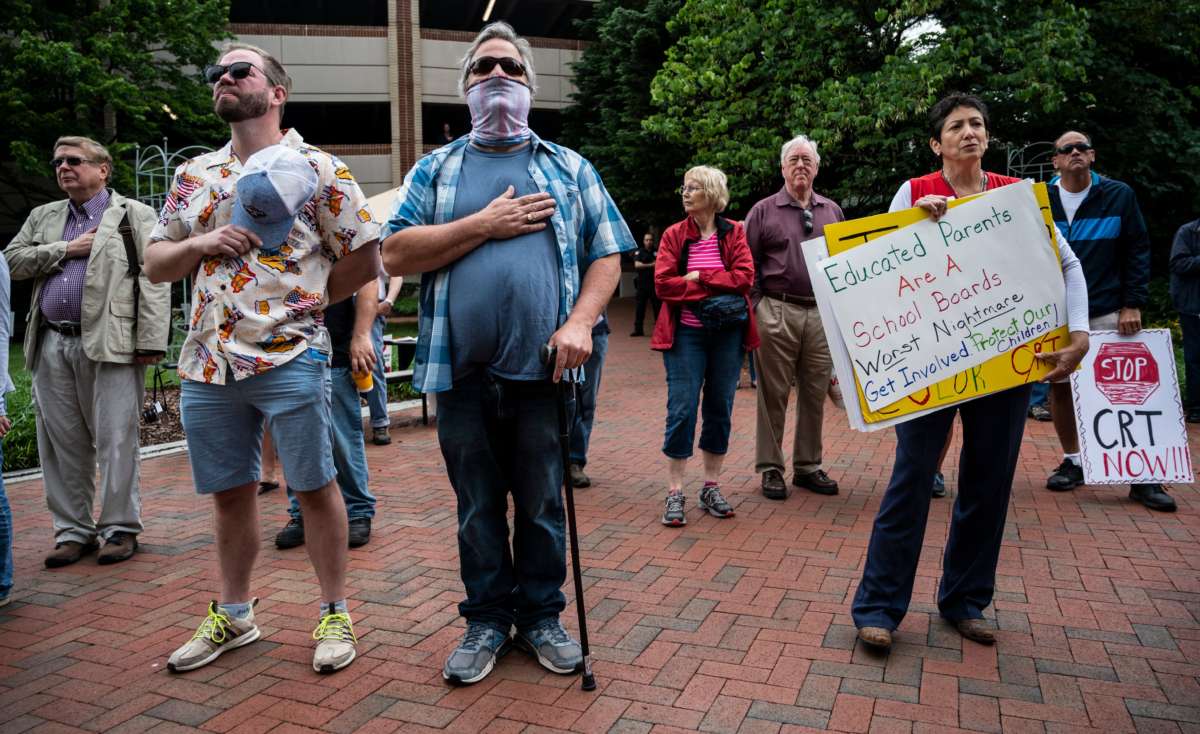 People hold up signs during a rally against "critical race theory" (CRT) being taught in schools at the Loudoun County Government center in Leesburg, Virginia, on June 12, 2021.