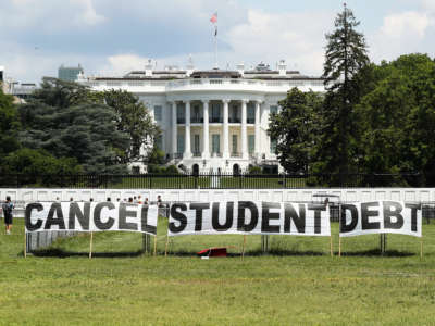 As college students around the country graduate with a massive amount of debt, advocates display a hand-painted sign on the Ellipse in front of The White House to call on President Joe Biden to sign an executive order to cancel student debt on June 15, 2021, in Washington, D.C.