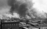 an aerial view of the Tulsa Race Riot with smoke billowing up from buildings