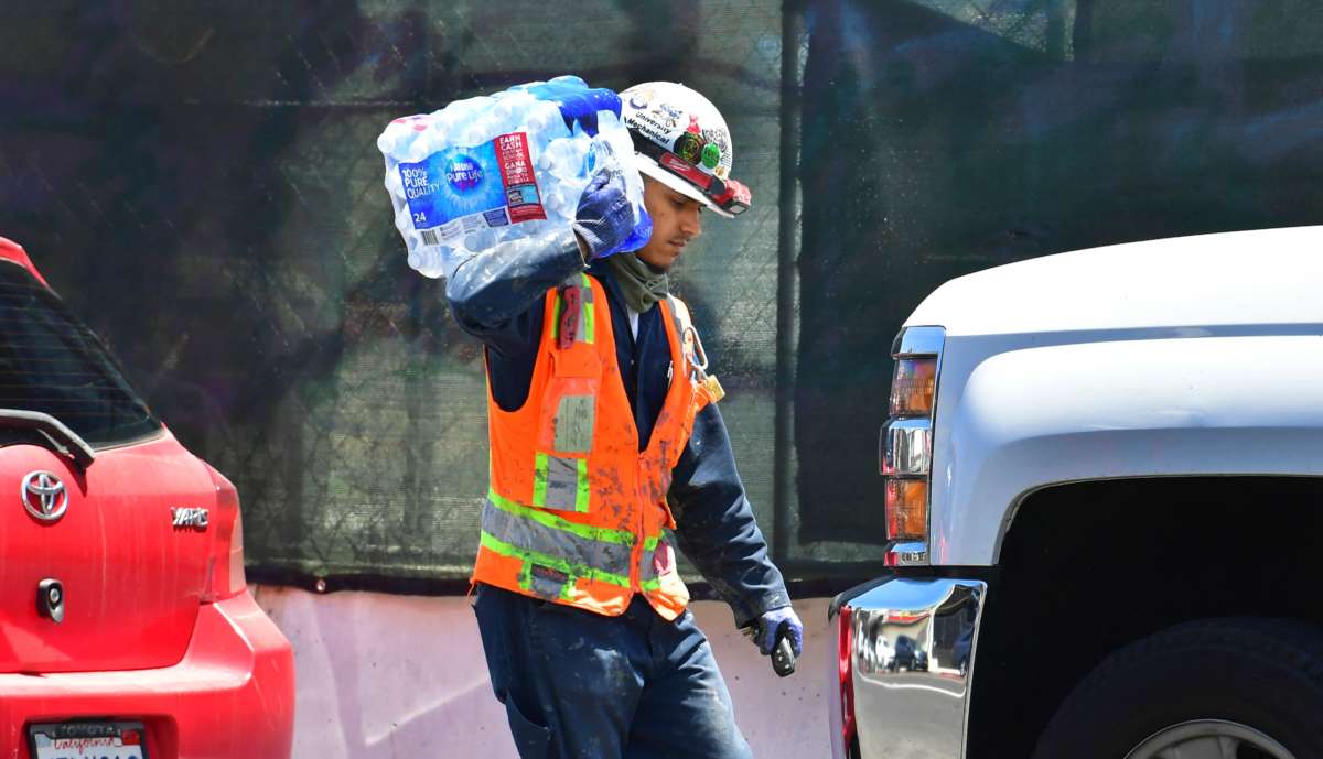 A construction worker carries a 24-pack of bottled water over his shoulder on June 14, 2021 in Los Angeles, where an early season heat wave was in full swing across much of California.