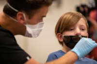 A medical worker administers a covid test on a child