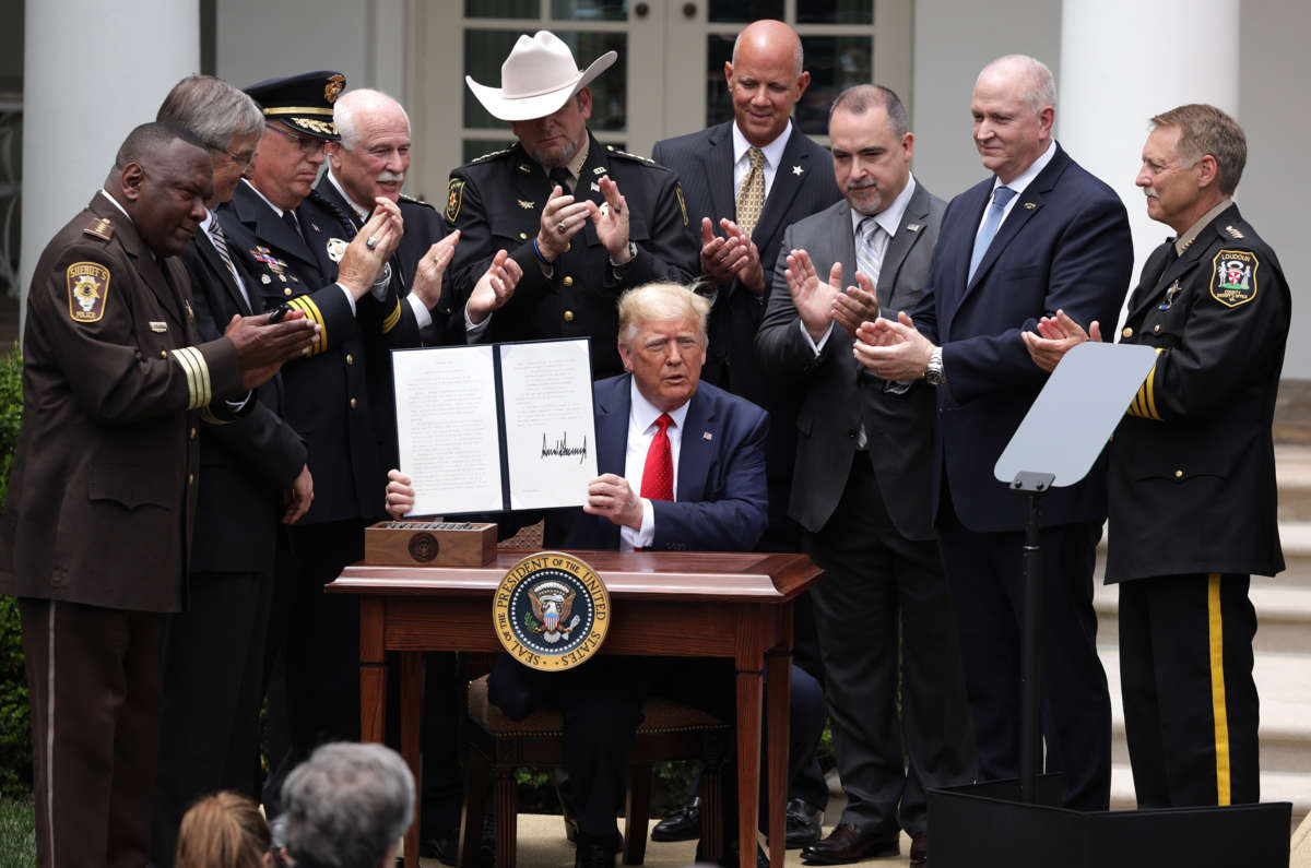 Donald Trump holds up his scribbles while surrounded by cops