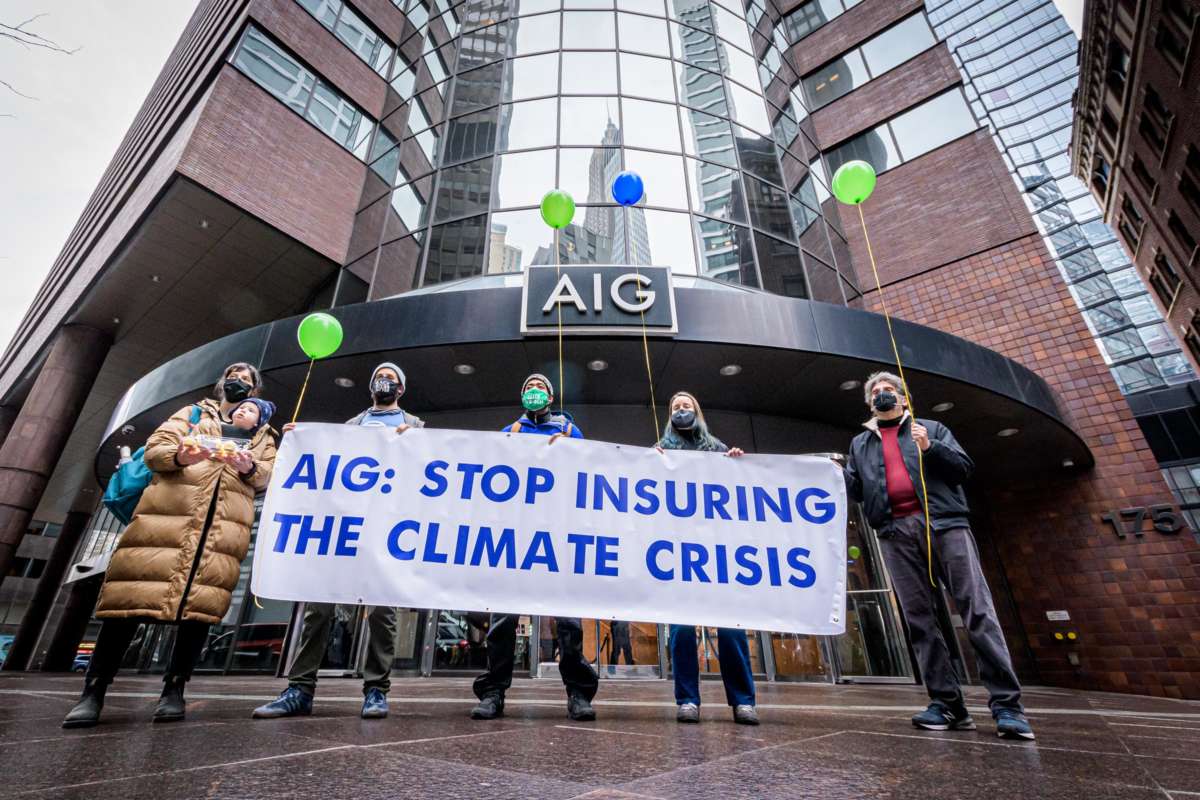 Protesters hold a sign reading "AIG: STOP INSURING THE CLIMATE CRISIS" during an outdoor protest
