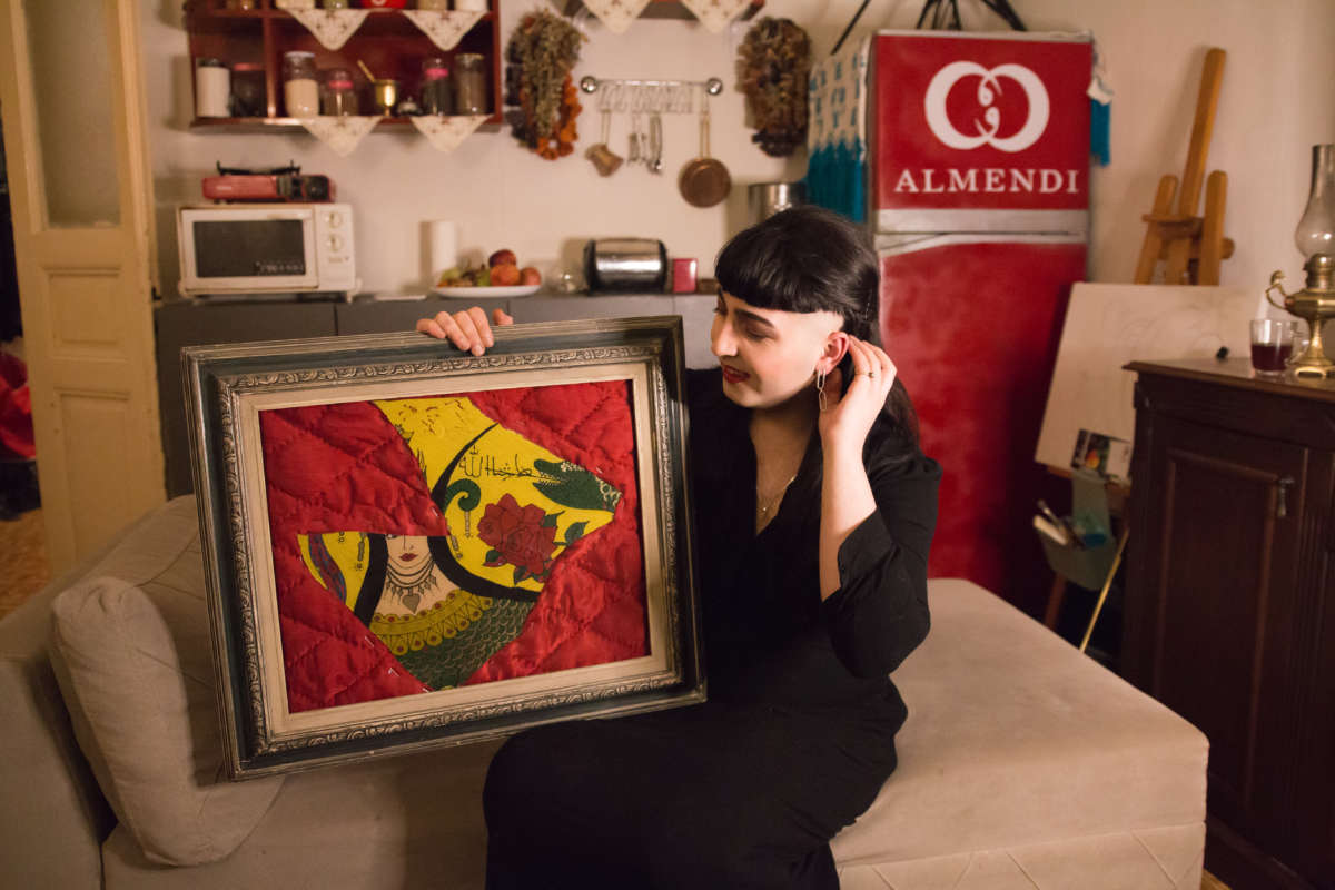 Çağlar Almendi with their art piece of a Shahmaran, half-woman, half-snake, and a traditional quilt.