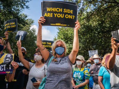 People display signs during the Georgetown to Austin March for Democracy rally on July 31, 2021 in Austin, Texas.