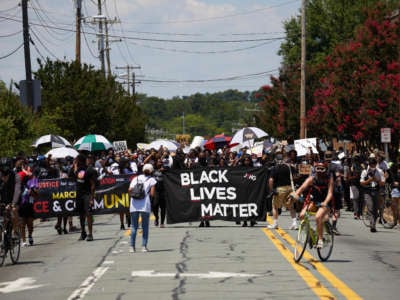 People march behind a Black Lives Matter banner during a street protest