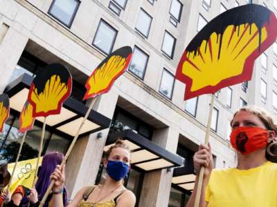 Protesters hold signs resembling the Shell logo dripping with oil