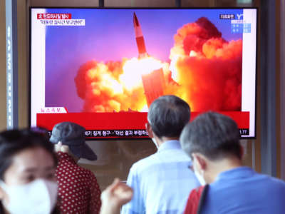 People are seen watching television footage of a missile launch