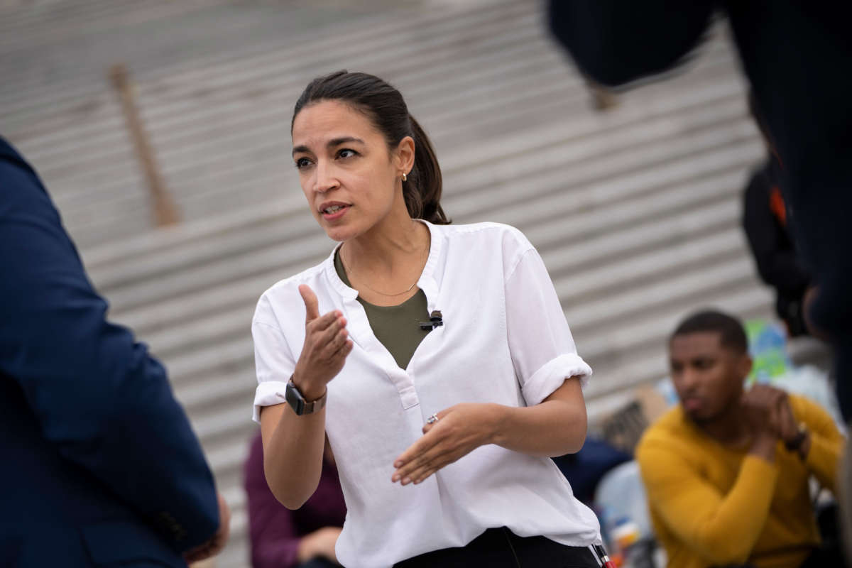 Rep. Alexandria Ocasio-Cortez talks with a reporter as she protests the expiration of the federal eviction moratorium on the House steps of the U.S. Capitol on August 3, 2021, in Washington, D.C.