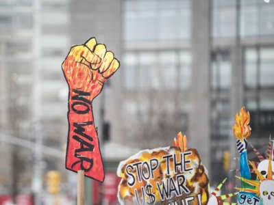 A marcher holds a sign that says "NO WAR" with a closed fist as protest outside of Trump International Tower during the Woman's March in the borough of Manhattan in New York on January 18, 2020.