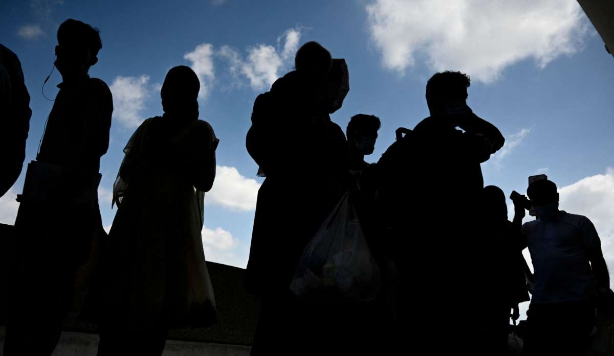 Refugees from Afghanistan wait to board a bus after arriving and being processed at Dulles International Airport in Dulles, Virginia, on August 23, 2021.