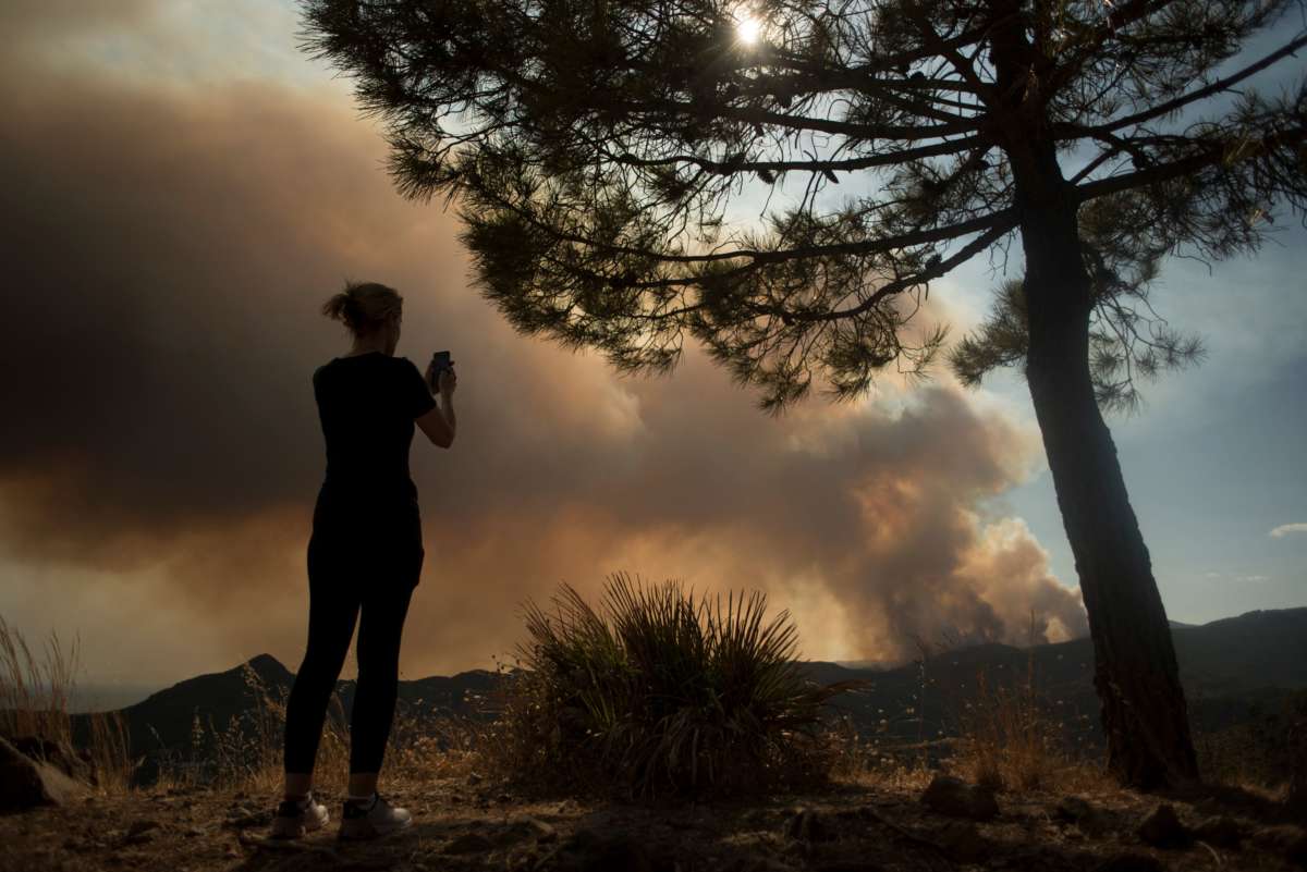 A person takes pictures of smoke columns rising from a wildfire in Sierra Bermeja mountain range in Malaga province, on September 9, 2021, in southern Spain.
