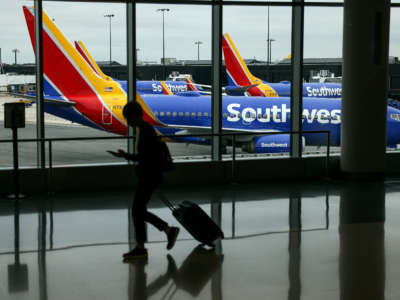 A traveler walks past a Southwest Airlines airplane as it taxies from a gate at Baltimore Washington International Thurgood Marshall Airport on October 11, 2021, in Baltimore, Maryland.