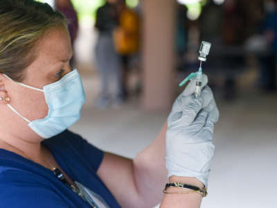 A health care worker with the Berks Community Health Center fills a syringe with a dose of COVID-19 vaccine at the Reading Area Community College campus in Reading, Pennsylvania, on September 14, 2021.