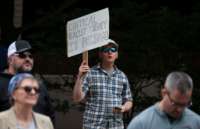 A man holds a sign reading "CRITICAL RACIST THEORY IS POISON" during a protest