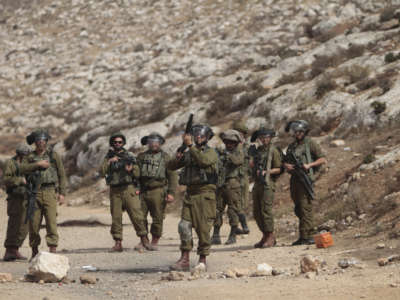 An Israeli soldier is seen aiming at Palestinian protesters, during a demonstration against Israeli settlements in the village of Beit Dajan near the West Bank city of Nablus on October 29, 2021.