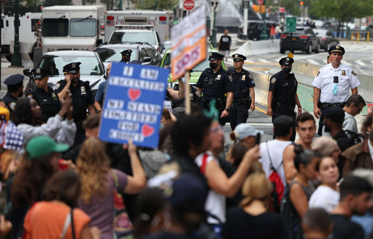 NYPD officers stand watch as people march as they protest against New York City's COVID-19 vaccine mandate for public school employees on October 4, 2021, in New York City.