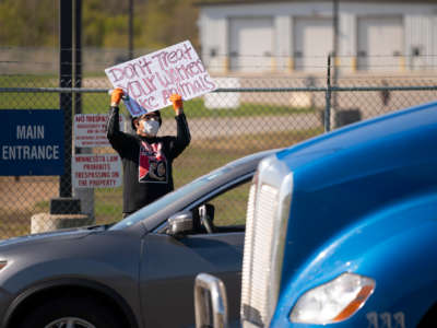 A protester holds a sign at the main entrance to the Pilgrim's Pride plant during a demonstration against unsafe working conditions on May 11, 2020.