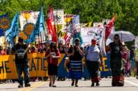 Climate activist and Indigenous community members hold a banner and flags during a rally and march against the Line 3 pipeline in Solway, Minnesota, on June 7, 2021.