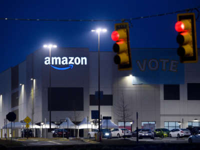 Amazon fulfillment center in Bessemer, Alabama, with banner reading Vote, seen past red stoplights