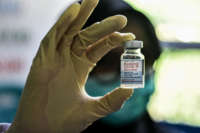 A health worker holds up a bottle of Moderna COVID-19 vaccine.