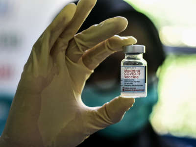 A health worker holds up a bottle of Moderna COVID-19 vaccine.