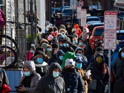 Hundreds of people wait in a line that stretched several blocks from the pantry for their turn to receive food at the La Colaborativa Food Pantry in Chelsea, Massachusetts, on November 23, 2021.