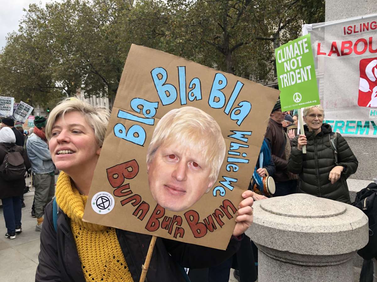 Protester holds a sign featuring Boris Johnson's face surrounded with the text "Bla Bla Bla While We Burn Burn Burn" during a COP26 demonstration in Trafalgar Square in London, U.K., on November 6, 2021.