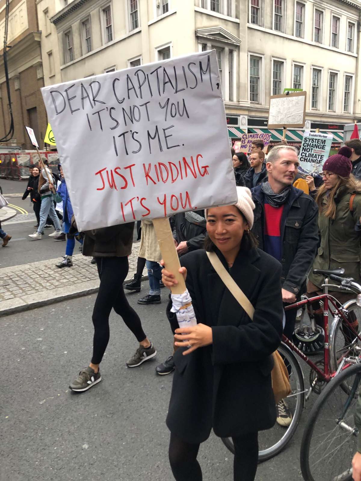 COP26 demonstrator holds a sign that says "DEAR CAPITALISM, IT'S NOT YOU, IT'S ME. JUST KIDDING IT'S YOU." in London, U.K., on November 6, 2021.