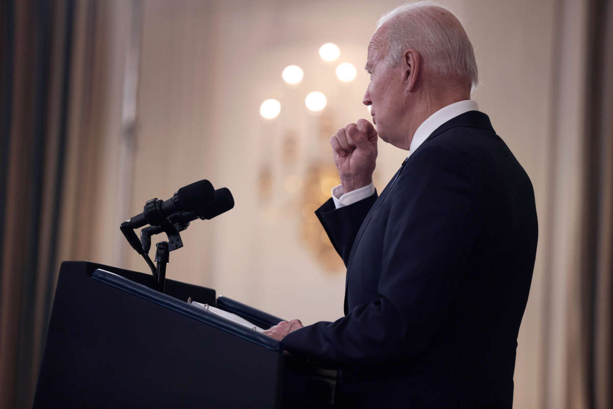 Joe Biden coughs into his hand at a podium