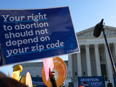 Abortion rights advocates demonstrate in front of the Supreme Court. A sign reads: Your right to abortion should not depend on your zip code.