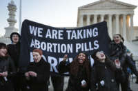 A bunch of people take abortion pills on the steps of the United States Supreme Court