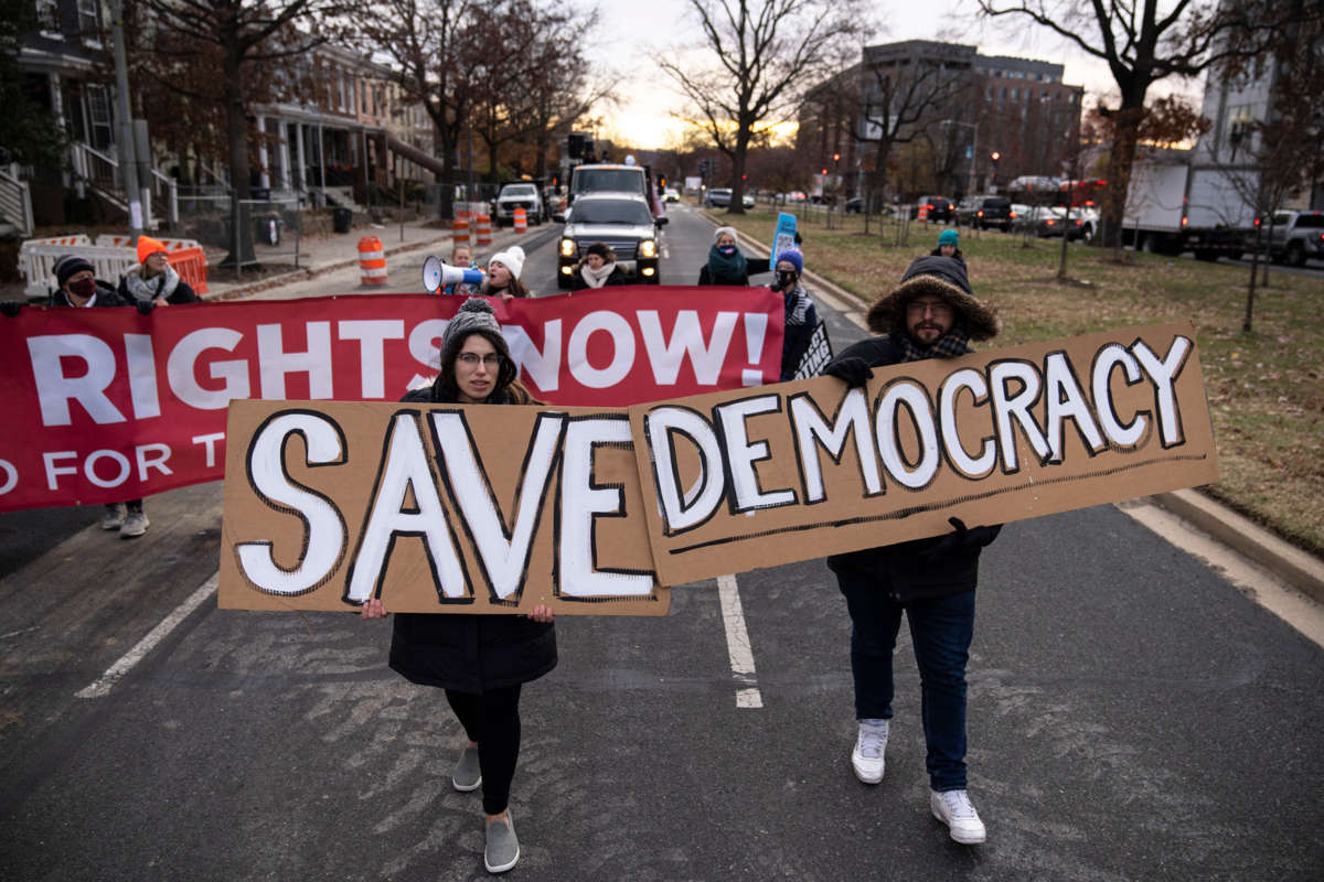 People march behind signs reading "SAVE DEMOCRACY!"