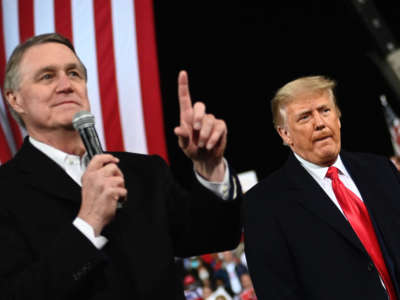 Sen. David Perdue gestures as he speaks next to President Donald Trump during a rally to support Republican Senate candidates at Valdosta Regional Airport in Valdosta, Georgia, on December 5, 2020.