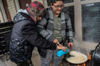 Two people cook rice on an outdoor grill