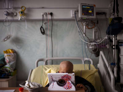 A small child looks at a tablet screen while in a hospital