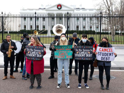 Activists hold festive signs calling on President Biden to cancel student debt and not resume student loan debt while musicians play joyful music, greeting the White House staff as they arrive to work on December 15, 2021, in Washington, D.C.