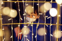 A little boy in a mask looks at a light display