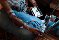 A dialysis patient looks at the tablet on their lap
