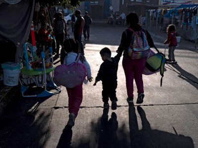 A family arrives at an improvised camp of asylum seekers and refugees at El Chaparral border crossing in Tijuana, Baja California state, Mexico, on December 6, 2021.