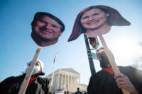 Protesters display cardboard cutouts of Justices Brett Kavanaugh and Amy Coney Barrett's faces