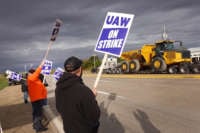 A truck hauls a piece of John Deere equipment from the factory past workers picketing outside of the John Deere Davenport Works facility on October 15, 2021, in Davenport, Iowa.