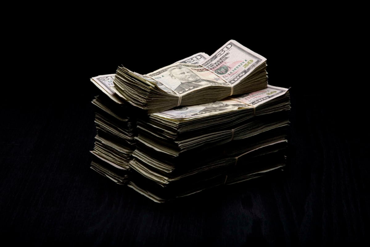 Stacks of $50 Bills on dark wooden table.