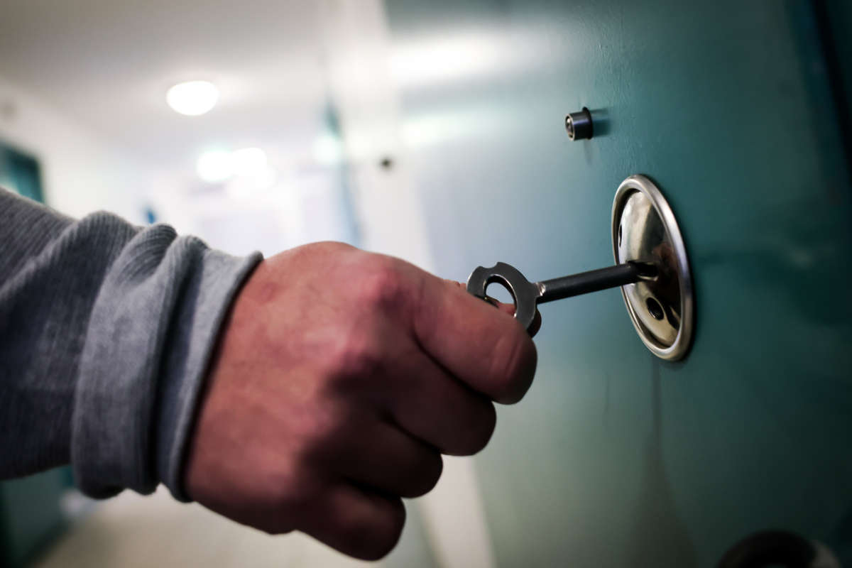 A man locks a cell door with a key