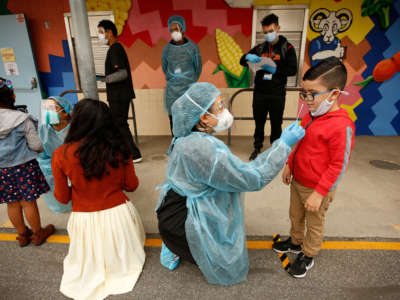 A kindergarten student gets a COVID-19 test from an EMT on the campus of Heliotrope Avenue Elementary School on April 13, 2021, in Maywood, California.